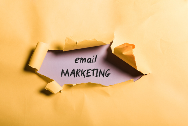 potrhaný oranžový papír s e-mailovým marketingovým písmem a válcovaný okraj na purpurové  - Fotografie, Obrázek