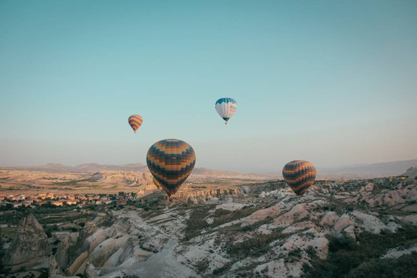 A long shot of multiple multi-colored hot air balloons floating high above mountains - Valokuva, kuva