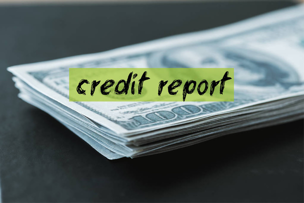 foco seletivo da pilha com notas de dólar perto de letras de relatório de crédito em preto
  - Foto, Imagem
