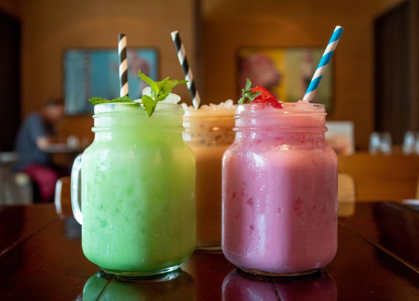 Closeup of three different flavored tasty Thai milk tea on a wooden table at a cafe - Foto, Imagen
