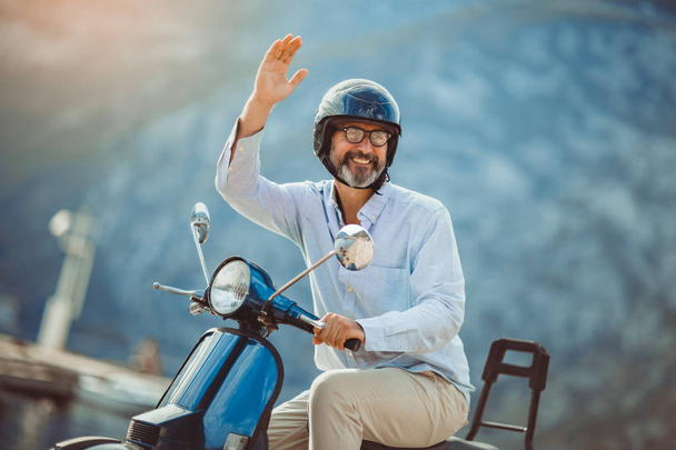 Volwassen man rijden motor scooter in Marina in de buurt van de zee. - Foto, afbeelding