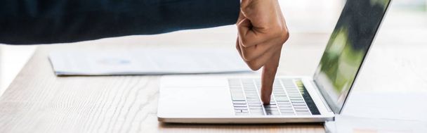 Panoramaaufnahme eines Mannes, der mit dem Finger auf Laptop-Tastatur zeigt  - Foto, Bild