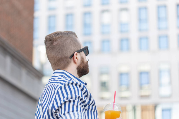 Bottom View portret van een stijlvolle jonge hipster man in spiegel glazen met SAP op de achtergrond van het Business Center. Urban Holiday in het weekend concept. - Foto, afbeelding