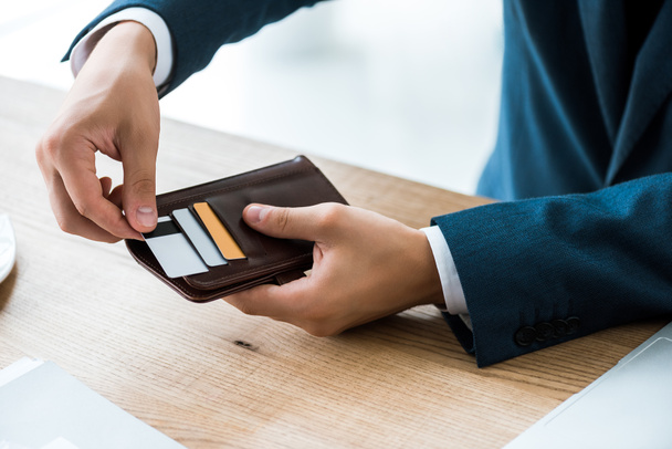 cüzdanını tutarken kredi kartına dokunan işadamının kırpılmış görünümü  - Fotoğraf, Görsel