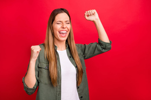 Photo of overjoyed successful nice aspired woman celebrating her victory while isolated with red background - 写真・画像