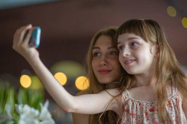 Tyttö ottaa selfien äitinsä tai siskonsa kanssa
 - Valokuva, kuva