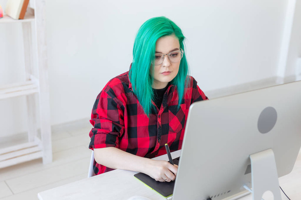 Designer, illustrator, artist and people concept - portrait of contemporary young woman with green hair using laptop and graphic tablet while working - 写真・画像