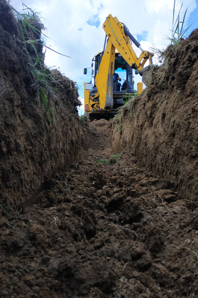 建設現場の溝を掘る黄色の掘削機、クローズアップ、空に対して. - 写真・画像