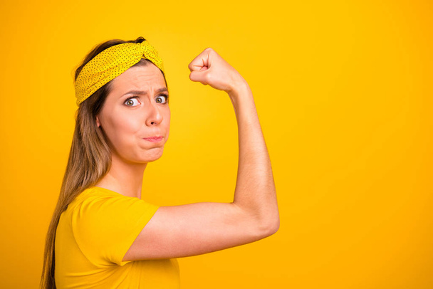 Closeup photo of beautiful lady trying hard to make hand muscle bigger wear casual t-shirt isolated yellow background - Фото, зображення