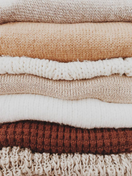 Een minimale stapel warme mooie vrouwelijke truien of pullovers met neutrale beige, bruine kleuren. Herfst-, herfst-of winter concept. Kerst patroon. - Foto, afbeelding