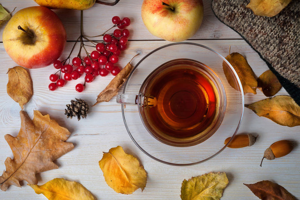 Cup of tea, autumn leaves and fruits on a wooden background. - Φωτογραφία, εικόνα