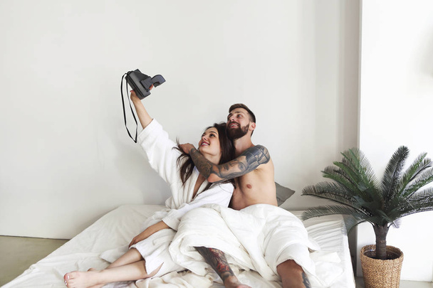 Ζευγάρι που ποζάρει στο κρεβάτι και παίρνει selfie το πρωί  - Φωτογραφία, εικόνα