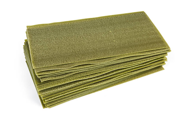 Folhas de lasanha de espinafre verde não cozido em um fundo branco
 - Foto, Imagem