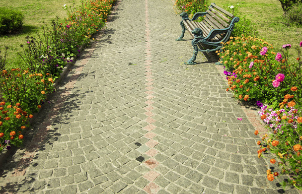 narrow paves alley way tile road between flower beds near bench for rest in walking time in European medieval city square  - Photo, Image