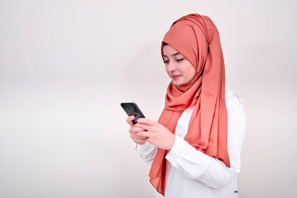 Muzułmańska kobieta wpisując wiadomość i patrząc jej ekran telefonu komórkowego, Dziewczyna muzułmańskich napisać wiadomość - Zdjęcie, obraz