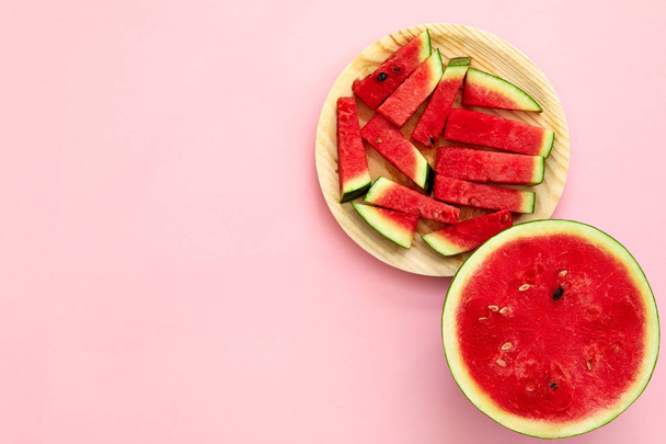 Watermeloen gesneden in de helft en segmenten geïsoleerd in Rose mist backgroun - Foto, afbeelding