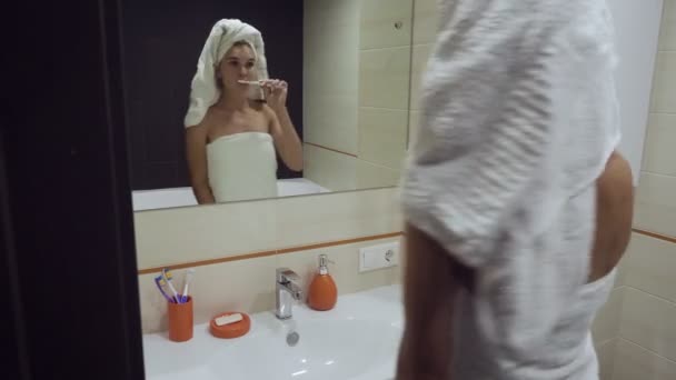 Mooie vrouw borstelen haar tanden en kijkt in de mirrorr. - Video