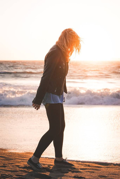 Beautiful vertical shot of a female walking on the Baker Beach shore in SF - Photo, Image