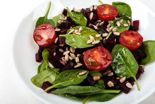 Healthy vegetarian food. Salad with beetroot, spinach, cherry tomatoes and seeds. - Photo, Image