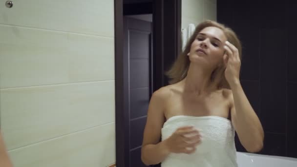 Jonge vrouw kijkt in de spiegel en recht haar in de badkamer. - Video