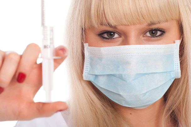 Close up of a young blonde nurse in a mask with a syringe. - Foto, Bild