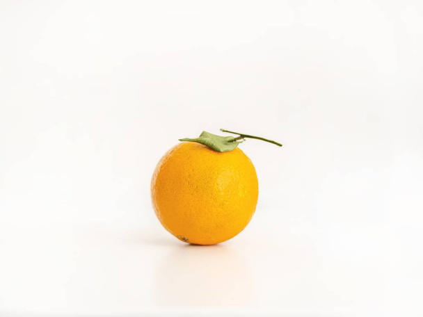 Closeup of an isolated whole orange with a leaf on a bright light pink background - Φωτογραφία, εικόνα