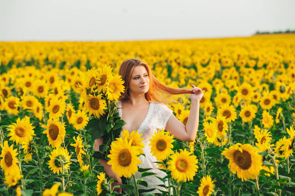 Beautiful girl in a huge yellow field of sunflowers.  - Foto, Imagem