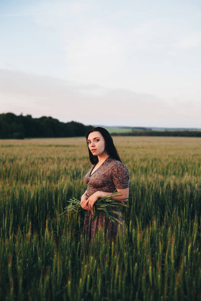 Beautiful young woman at sunset in the field - Foto, afbeelding
