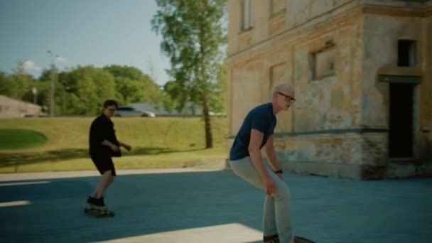Two Cool Young Guys Riding Longboard and Skateboard Through Stylish Hip Cultural Part of the City. Skateboarding in Post Industrial Neighbourhood. Slow Motion Following Shot - Materiał filmowy, wideo