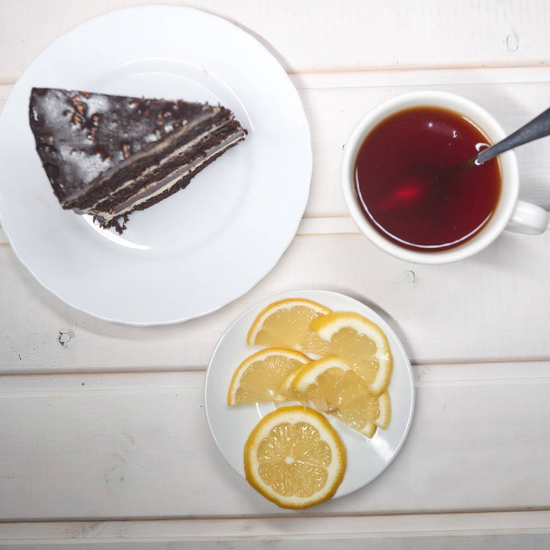 rebanada de pastel de chocolate con una taza de té blanco
 - Foto, Imagen