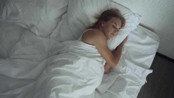 Woman awakening in comfortable cozy bed stretching and gets up. - Video, Çekim