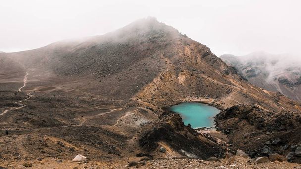 A beautiful aerial shot of a small lake in the middle of the desert near a mountain on a foggy day - Foto, afbeelding