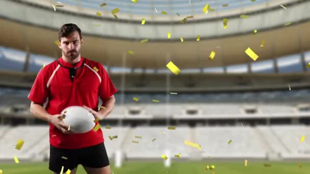 Animation of a Caucasian male rugby player playing with a ball and looking to camera with golden confetti falling and a sports stadium in the background - Materiał filmowy, wideo