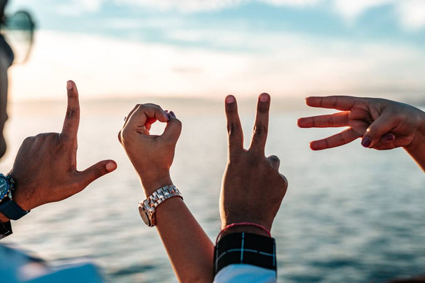 Dedos de un grupo de amigos formando letras que deletrean "AMOR" sobre un hermoso fondo natural
 - Foto, Imagen
