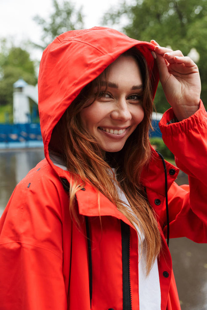 Image of joyful young woman 20s in colorful raincoat walking thr - Fotoğraf, Görsel