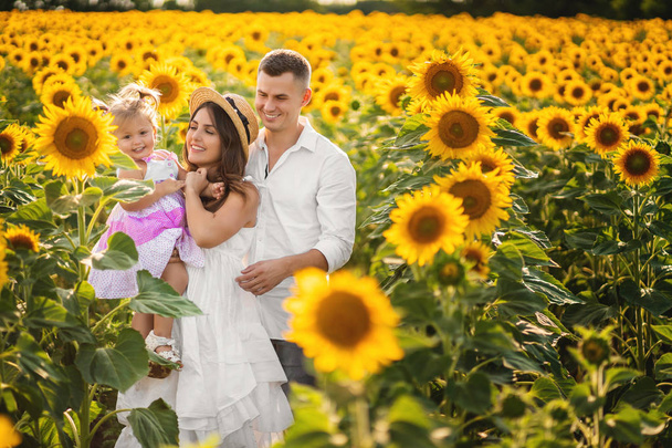 Happy family of three on a walk among flowering field. Summer fi - Photo, Image