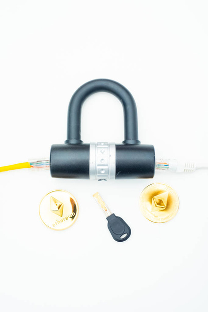 Dois cabos de rede de computador passando por uma fechadura com uma chave e uma moeda criptomoeda
 - Foto, Imagem