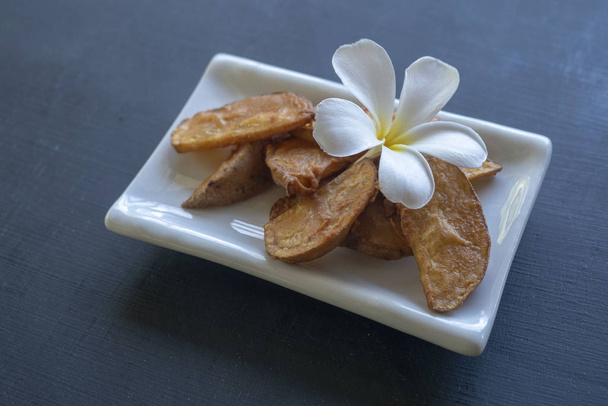 Chips on a white plate decorated with a tropical flower - Fotoğraf, Görsel