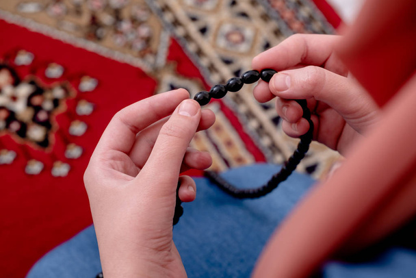 イスラム教徒の女性の祈り、イスラム教徒の女の子は、敷物とロザリオビーズで祈る手を開きます - 写真・画像