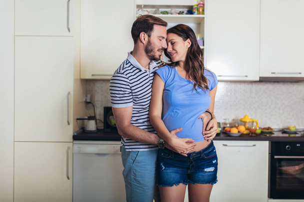 Pregnant woman with husband in the kitchen - Фото, изображение