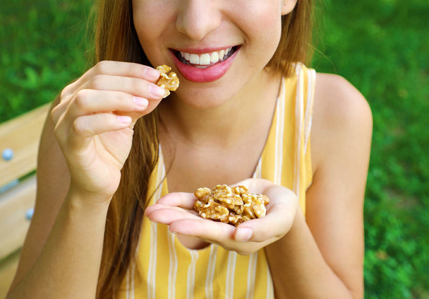 Lähikuva tunnistamaton tyttö syö saksanpähkinöitä puistossa
. - Valokuva, kuva