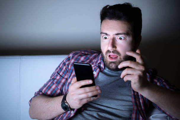 Surprised man expression using phone at night - Photo, Image