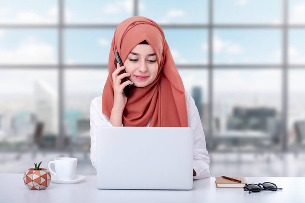 Muslimská žena pracuje s počítačem, s muslimskou muslimské dívkou v kanceláři a mluví na mobilním telefonu, odborné pomoci, kontaktu nebo konceptu zákaznického servisu - Fotografie, Obrázek