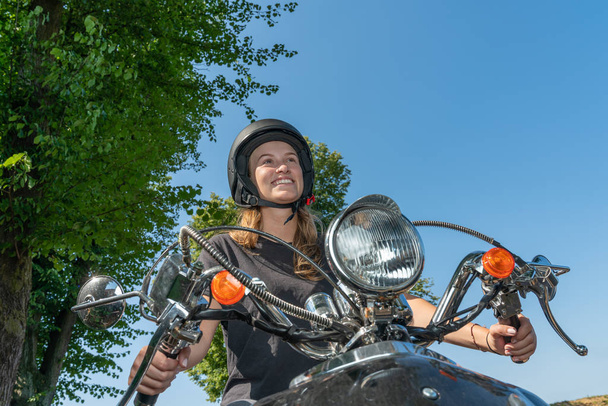 a young woman rides motor scooter and smiles - Zdjęcie, obraz