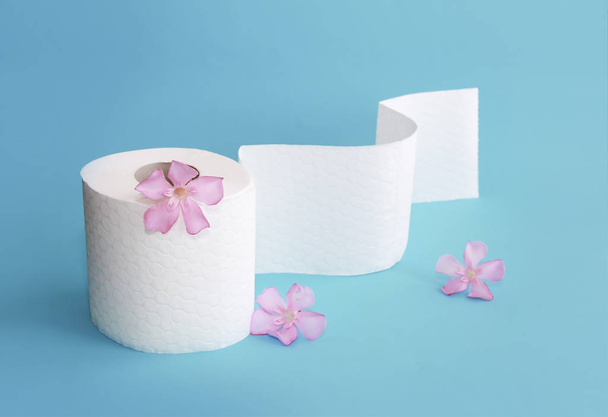 white toilet paper roll with flowers decor on a blue background - Photo, Image