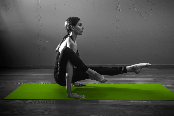 Black white photo of Young beautiful woman brunette in black clothes practice yoga in dark studio green mat Sport meditation monochrome - Zdjęcie, obraz