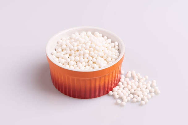 Perles de tapioca ou graines de sagu dans un ramequin orange, isolées sur fond blanc
 - Photo, image