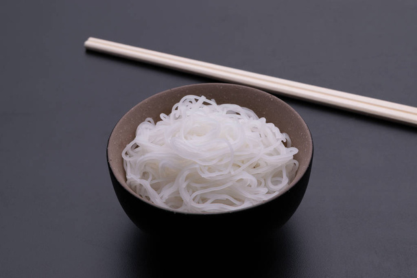 Cooked rice noodle Thai style in bowl with chopsticks isolated on black background - Photo, Image