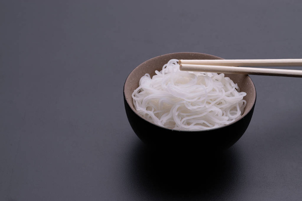 Cooked rice noodle Thai style in bowl with chopsticks isolated on black background - Photo, Image