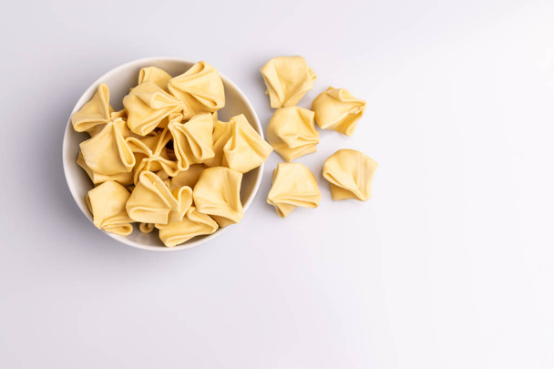 Top view of Fagottini Tortellini pasta in a white bowl isolated in white background, soft light - Foto, Bild